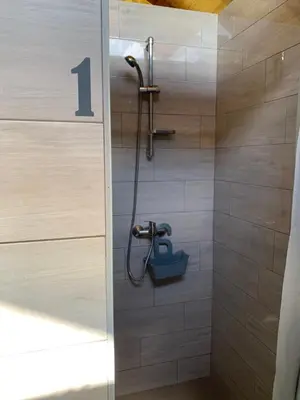 a shower with a number one on the wall at Kuća za odmor KRNJAIĆ,porodični KAMP in Bosanski Novi
