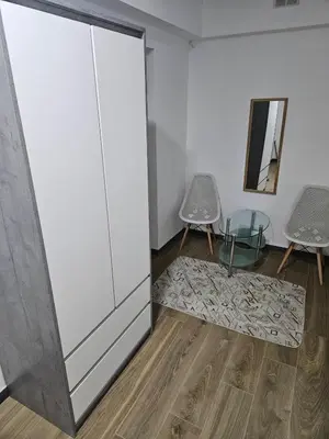 a room with a large white cabinet and two chairs at Apartman u centru Prnjavor in Prnjavor