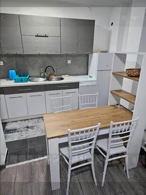 a kitchen with a wooden table and two chairs at Apartman u centru Prnjavor in Prnjavor