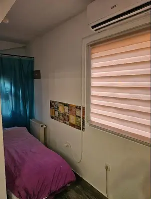 a bedroom with a window and a bed with purple sheets at Apartman u centru Prnjavor in Prnjavor