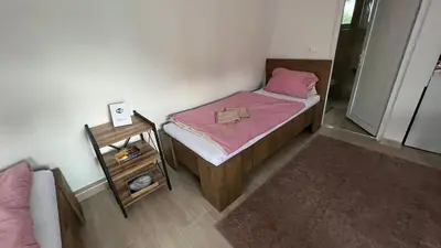 a small bedroom with a bed with pink sheets and a table at City apartment 3 in Visoko
