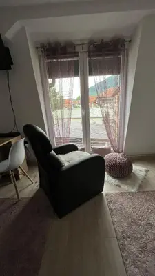 a black chair in a living room with a window at City apartment 3 in Visoko