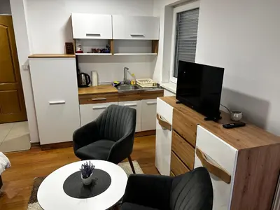 a living room with a table and chairs and a kitchen at Apartmani Venci Travnik in Travnik