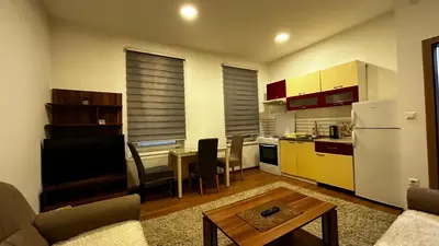 a living room with a kitchen with a table and a refrigerator at Apartmani Venci Travnik in Travnik