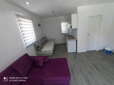 a living room with a purple couch and a kitchen at Apartmani Kula in Tuzla
