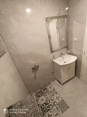 a bathroom with a sink and a shower with a mirror at Apartmani Kula in Tuzla