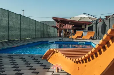 a swimming pool with orange chairs and a fence at Holiday home LOTUS in Bihać