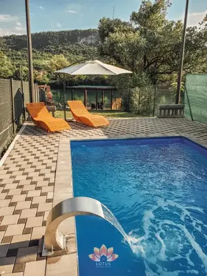 a swimming pool with orange chairs and an umbrella at Holiday home LOTUS in Bihać