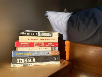 a stack of books sitting on top of a bed at Mountain Heart House in Bosanski Petrovac