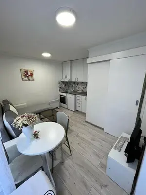a living room with a white table and a kitchen at Stan Centar 1 in Banja Luka