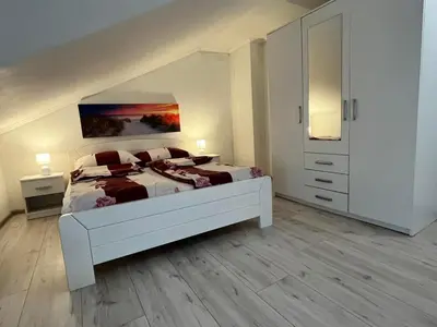 a white bedroom with a large bed and a white cabinet at Stan Centar 1 in Banja Luka