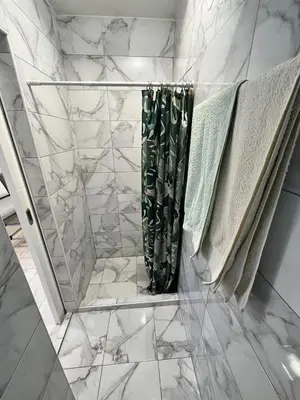a bathroom with a shower with white marble walls at Stan Centar 1 in Banja Luka
