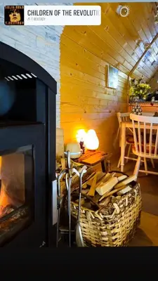 a living room with a fireplace and a table and a dining room at Planinska brvnara in Kupres