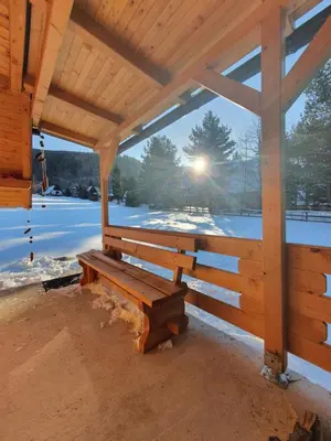 a wooden bench in a pavilion with the sun shining at Planinska brvnara in Kupres