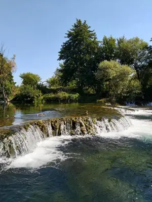 a waterfall in the middle of a river at Šadrvan Una Apartment in Bihać
