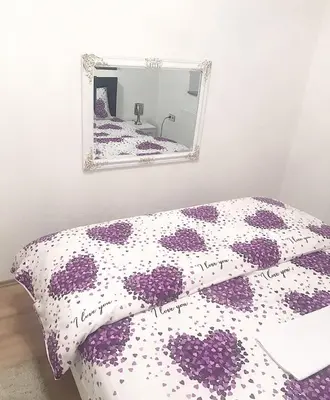 a bedroom with a purple and white bed with a mirror at Apartman Dunja II in Prijedor