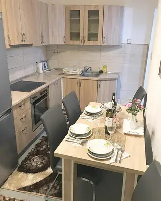 a kitchen with a wooden table with chairs and a dining room at Apartman Dunja II in Prijedor