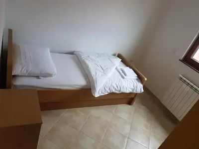a bedroom with a bed with white sheets and a window at Apartmani Kuprešak in Banja Vrućica