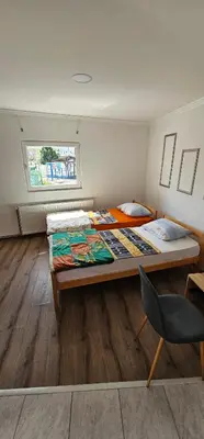 a room with two beds and a chair in it at Apartmani Roki in Tuzla