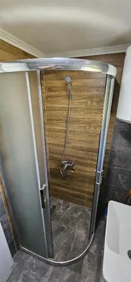 a shower in a bathroom with a wooden wall at Apartmani Roki in Tuzla