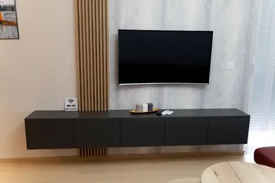 a black entertainment center with a flat screen tv on a wall at Apartman SLOL in Banja Luka