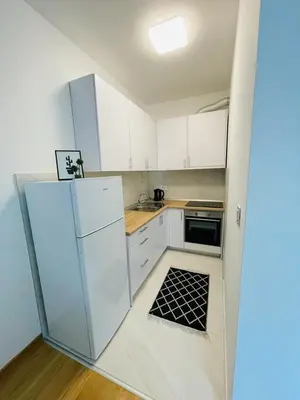 a kitchen with white cabinets and a black and white rug at Apartment HOLIDAY in Banja Luka