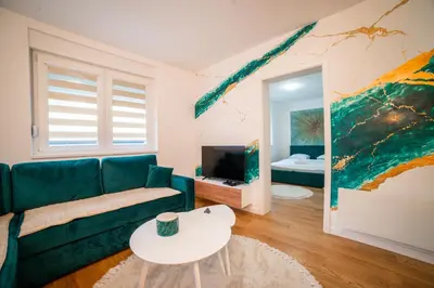 a living room with a green couch and a tv at Apartment Vila Idila in Tuzla
