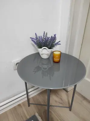 a glass table with a vase with purple flowers on it at Welcome Apartman in Tuzla