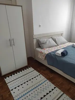 a bedroom with a bed and a wardrobe and a rug at Welcome Apartman in Tuzla
