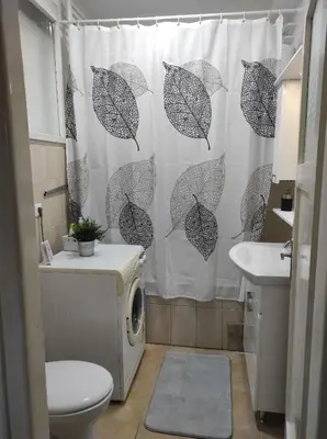 a bathroom with a shower curtain with umbrellas at Welcome Apartman in Tuzla