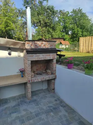 a brick fireplace sitting on top of a patio at Welcome Apartman in Tuzla