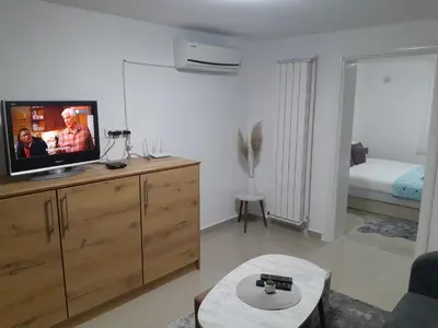 a living room with a tv on a wooden dresser at Apartmani BET Gradačac 1 Maj broj 24 in Gradačac