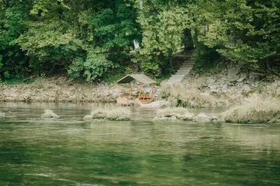 a picnic table sitting on the bank of a river at Apartments MoonRiver in Bihać