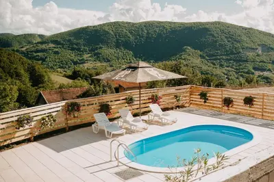 a pool with chairs and an umbrella on a patio at Vidovo Domacinstvo in Banja Luka
