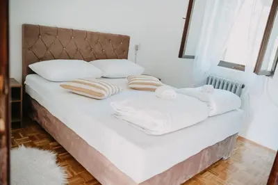 a bed with white blankets and pillows on it at Vidovo Domacinstvo in Banja Luka