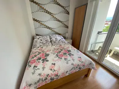a small bedroom with a bed with a floral bedspread at Apartman Citylux in Bihać