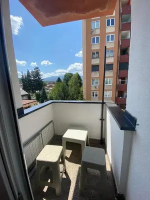 a balcony with two stools and a view of a building at Apartman Citylux in Bihać