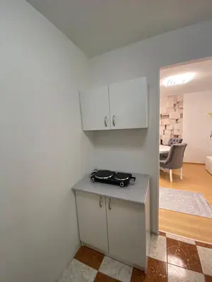 a white kitchen with a counter and a living room at Apartman Citylux in Bihać