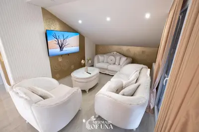 a living room with white chairs and a tv at Villa Mermaid of Una in Bihać