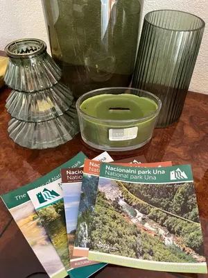 a table with magazines and a green bowl and a vase at Soko holiday home Bihac in Bihać
