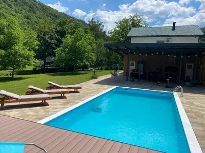 a swimming pool with two benches and a house at Soko holiday home Bihac in Bihać