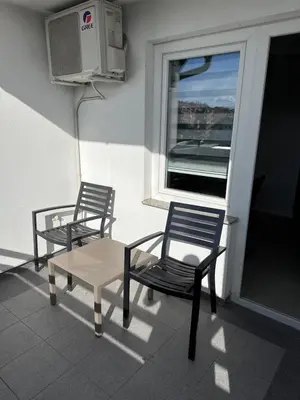 two chairs and a table on a balcony with a window at XL Apartman in Teslić