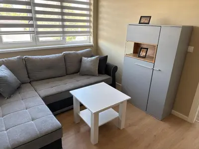 a living room with a couch and a white refrigerator at XL Apartman in Teslić