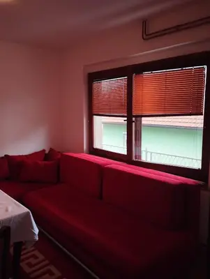 a living room with a red couch and two windows at Apartmani Emir in Visoko