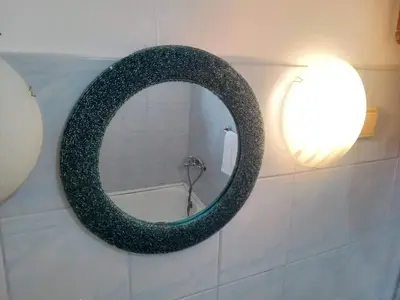 a round mirror on a wall with a light at Apartmani Emir in Visoko
