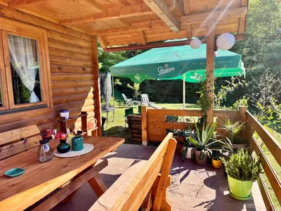 a wooden porch with a table and an umbrella at Brvnaria in Slatina Varoš