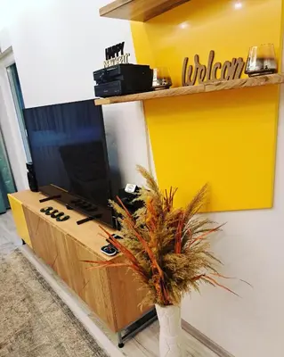 a room with a desk with a tv and a yellow wall at Apartman Mosaic in Doboj