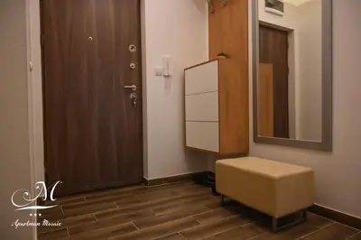 a bathroom with a mirror and a stool next to a door at Apartman Mosaic in Doboj