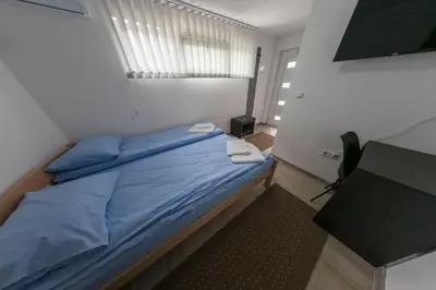 a bedroom with a bed with blue sheets and a window at Konak kod Hame in Bihać