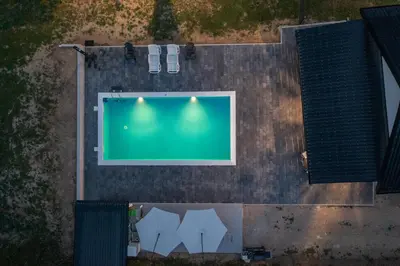 an overhead view of a swimming pool with four white umbrellas at Vikendica Lohovo in Bihać